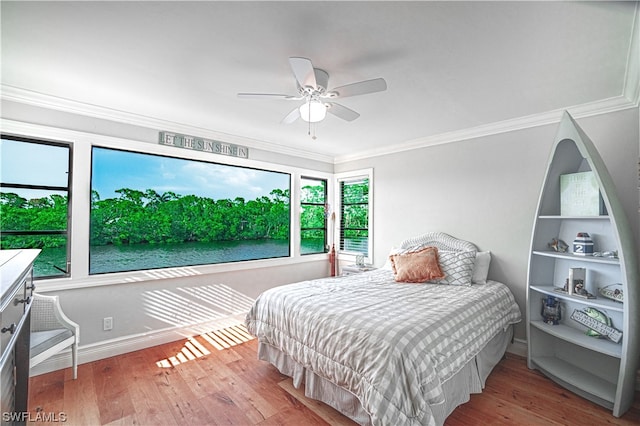 bedroom featuring crown molding, light hardwood / wood-style floors, ceiling fan, and a water view