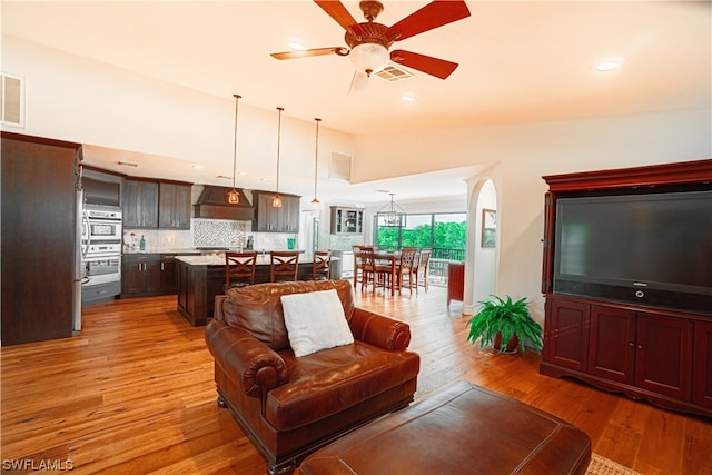 living room with ceiling fan with notable chandelier and light wood-type flooring