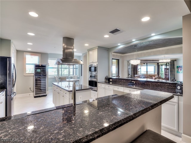 kitchen featuring white cabinetry, island range hood, stainless steel appliances, and a center island