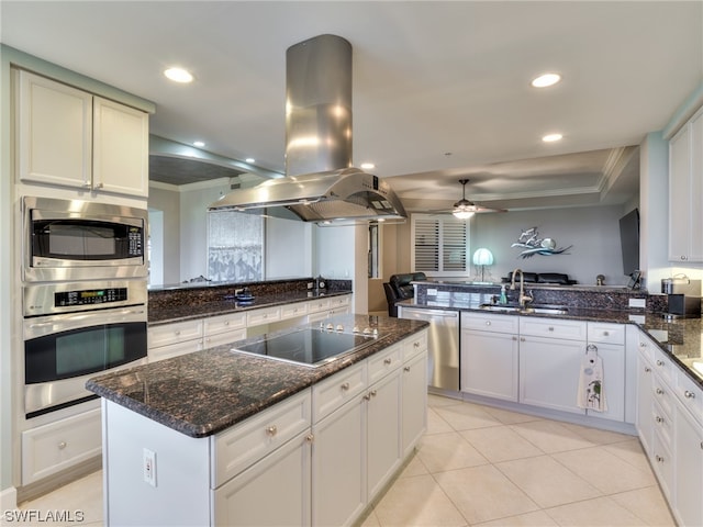 kitchen with sink, appliances with stainless steel finishes, island range hood, kitchen peninsula, and dark stone counters