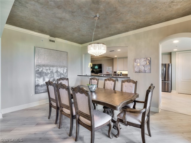 dining area featuring an inviting chandelier, ornamental molding, and light wood-type flooring