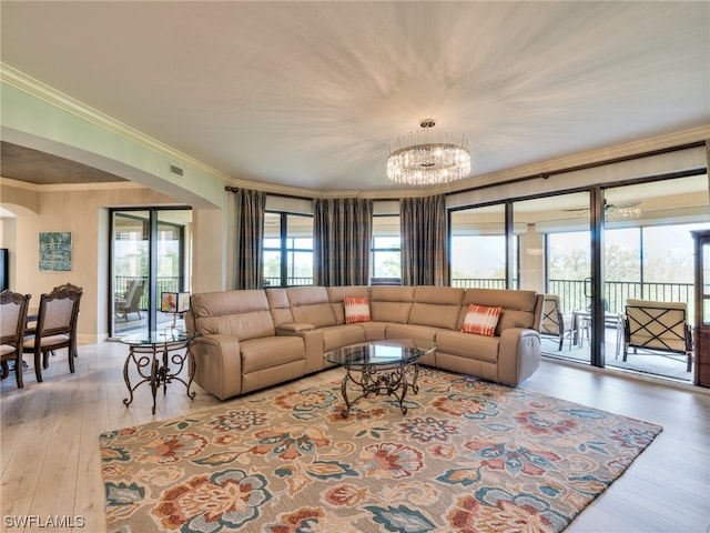 living room featuring an inviting chandelier, crown molding, and light wood-type flooring