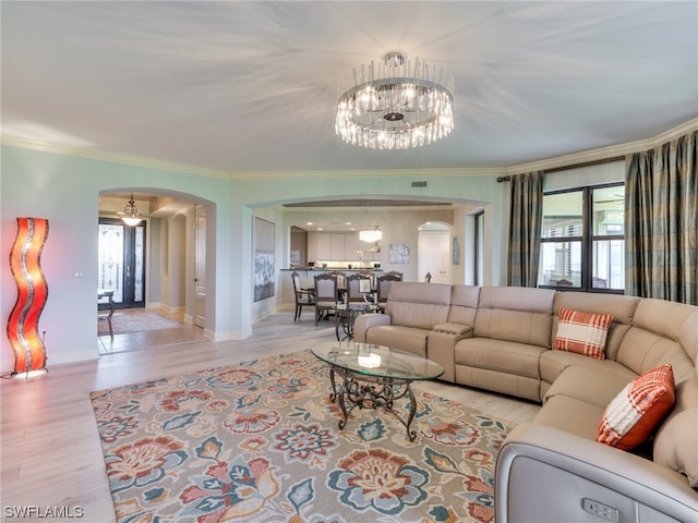 living room with an inviting chandelier, ornamental molding, and light hardwood / wood-style floors