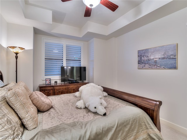 carpeted bedroom featuring a raised ceiling and ceiling fan