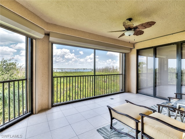 sunroom / solarium with a water view, a healthy amount of sunlight, and ceiling fan