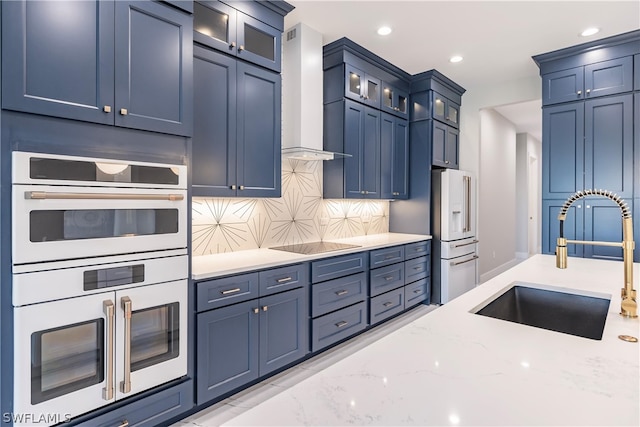 kitchen featuring light stone countertops, custom exhaust hood, blue cabinetry, backsplash, and sink