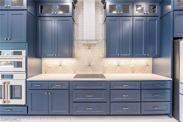 kitchen with blue cabinets, black electric cooktop, backsplash, and double oven