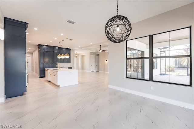 kitchen with ceiling fan, an island with sink, decorative light fixtures, backsplash, and light tile floors