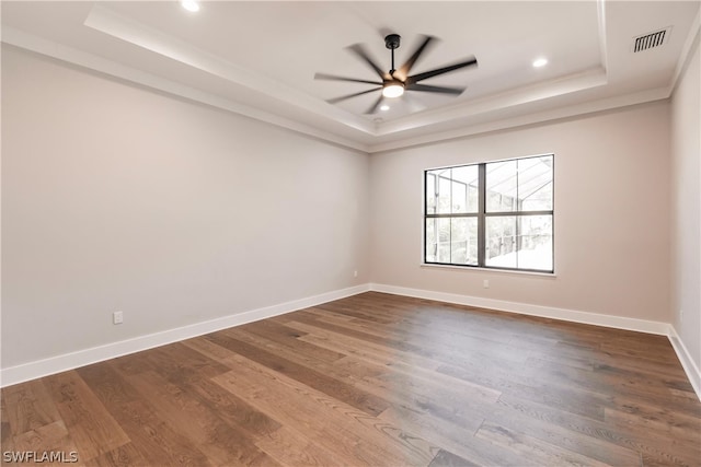 unfurnished room with ceiling fan, dark hardwood / wood-style flooring, and a tray ceiling