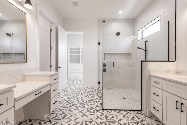 bathroom with tiled shower, tile flooring, and vanity