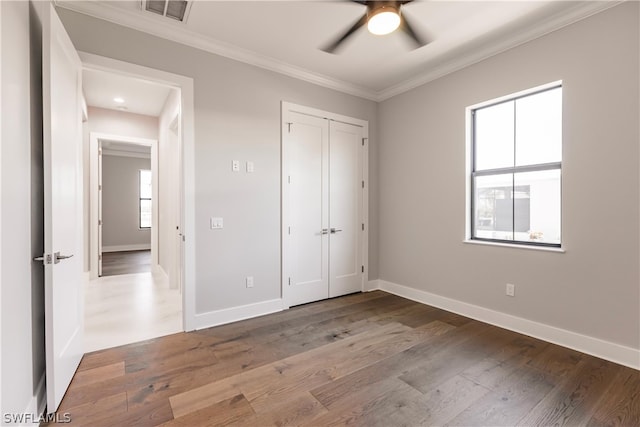 unfurnished bedroom with hardwood / wood-style floors, ceiling fan, crown molding, and multiple windows