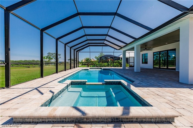 view of pool with glass enclosure, an in ground hot tub, a patio area, ceiling fan, and a yard