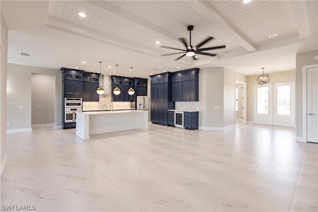 kitchen featuring a center island with sink, beam ceiling, light tile floors, and pendant lighting