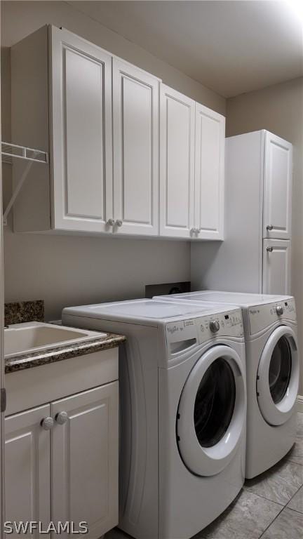 clothes washing area with separate washer and dryer and cabinets