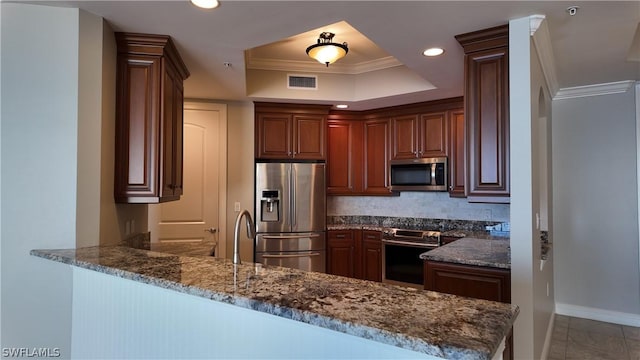 kitchen with tasteful backsplash, dark stone counters, kitchen peninsula, stainless steel appliances, and crown molding