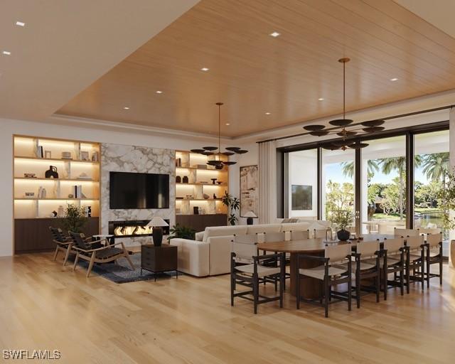 dining area featuring a fireplace, light hardwood / wood-style flooring, ceiling fan, and a raised ceiling