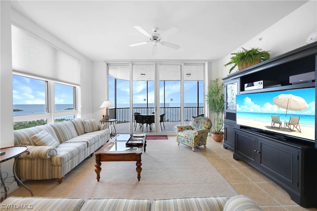 living room with light tile floors, a wall of windows, ceiling fan, and a water view