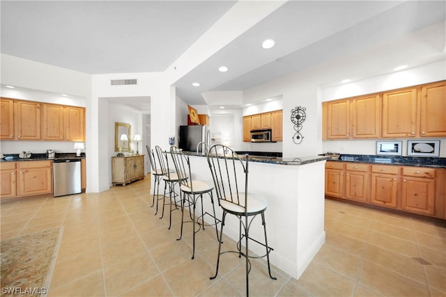 kitchen with a breakfast bar area, stainless steel appliances, and light tile flooring