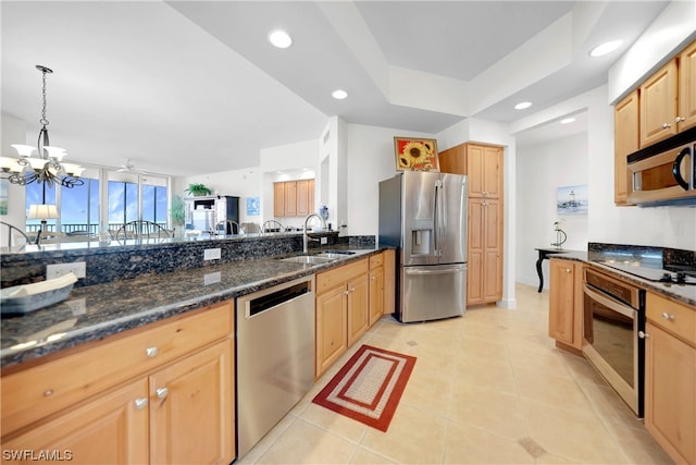 kitchen featuring stainless steel appliances, light tile floors, an inviting chandelier, dark stone counters, and sink