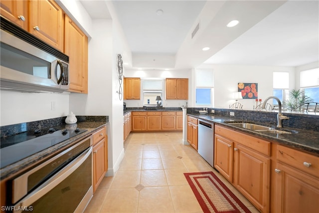 kitchen with dark stone counters, light tile flooring, sink, and stainless steel appliances