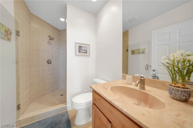 bathroom with toilet, tiled shower, large vanity, and tile flooring