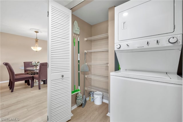 laundry area with stacked washing maching and dryer and light hardwood / wood-style flooring