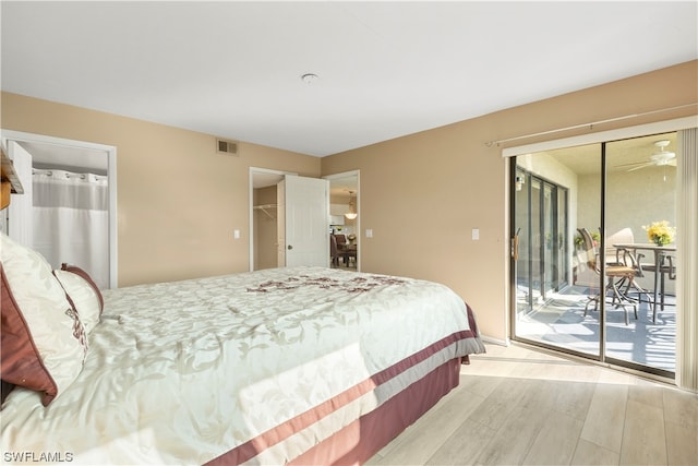 bedroom featuring a walk in closet, light hardwood / wood-style floors, a closet, and access to exterior