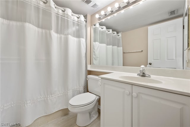 bathroom featuring toilet, large vanity, and wood-type flooring