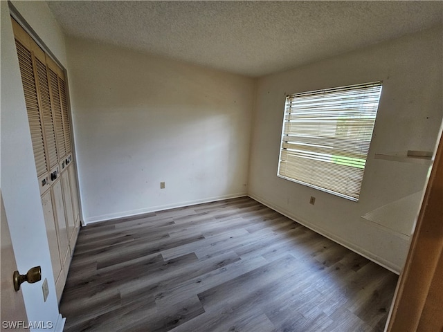 spare room featuring a textured ceiling and dark wood-type flooring