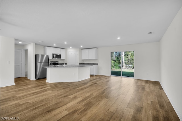 kitchen featuring a center island with sink, white cabinetry, light wood-type flooring, and stainless steel appliances