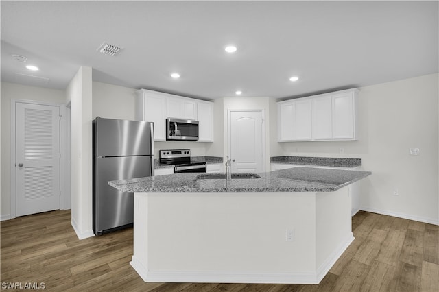 kitchen with an island with sink, white cabinetry, light hardwood / wood-style floors, and stainless steel appliances