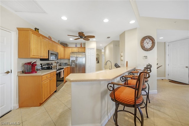 kitchen with a breakfast bar area, light tile flooring, ceiling fan, and appliances with stainless steel finishes