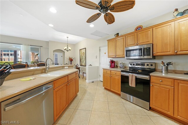 kitchen with hanging light fixtures, ceiling fan with notable chandelier, appliances with stainless steel finishes, sink, and light tile floors