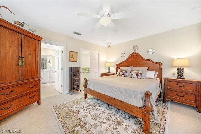 bedroom featuring ceiling fan, ensuite bathroom, and light colored carpet