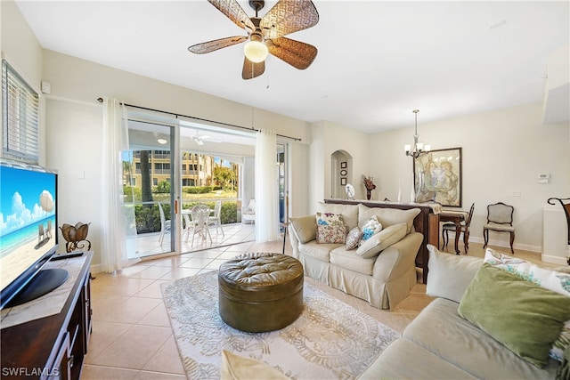 tiled living room with ceiling fan with notable chandelier