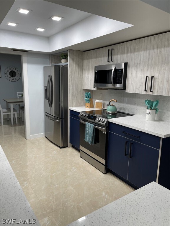 kitchen featuring decorative backsplash, blue cabinets, and appliances with stainless steel finishes