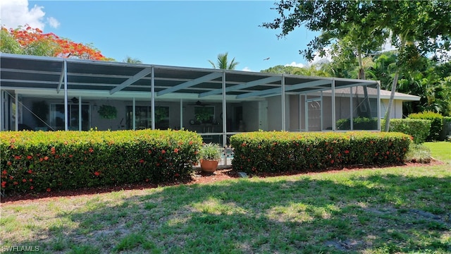 rear view of house with a lawn, ceiling fan, and a lanai