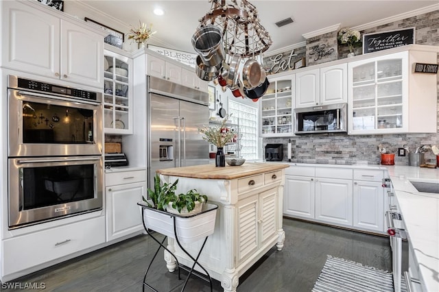 kitchen featuring appliances with stainless steel finishes, white cabinetry, dark hardwood / wood-style floors, and a center island