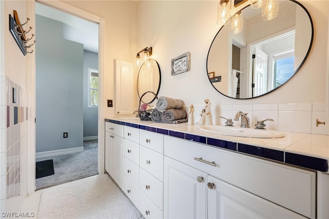 bathroom with tasteful backsplash, large vanity, and dual sinks