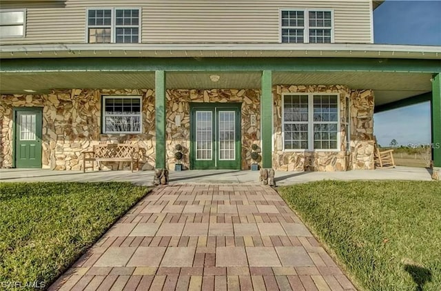 view of exterior entry with a yard and covered porch