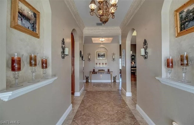 hall with light tile flooring, a chandelier, and ornamental molding