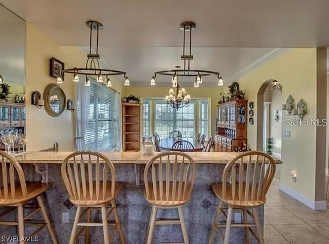 interior space with pendant lighting, light tile floors, and a breakfast bar