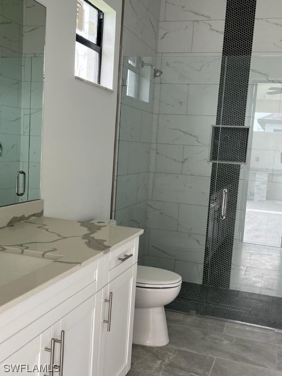 bathroom with toilet, a shower with shower door, and vanity