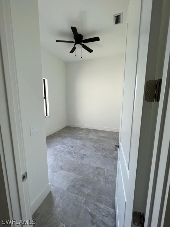 spare room featuring dark tile floors and ceiling fan