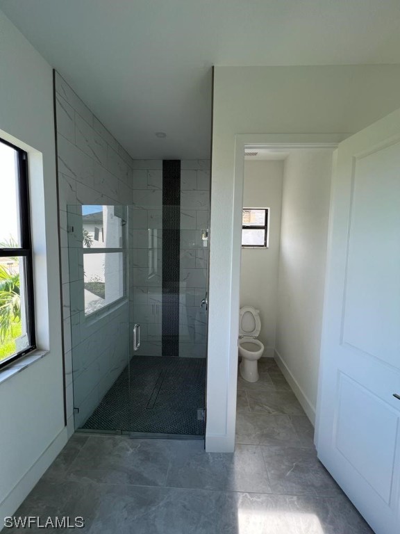 bathroom with walk in shower, toilet, and tile floors