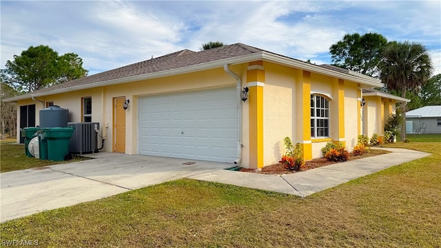 view of front facade with a front yard, a garage, and central AC