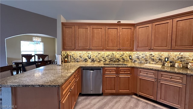 kitchen with light wood-type flooring, dishwasher, sink, a notable chandelier, and kitchen peninsula