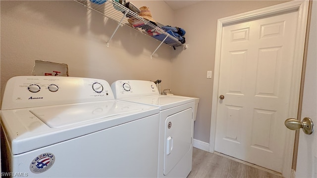 clothes washing area featuring light hardwood / wood-style flooring and washing machine and dryer