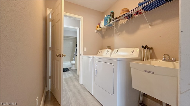 washroom featuring light hardwood / wood-style flooring, sink, and washing machine and dryer