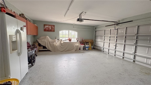 garage with a garage door opener and white refrigerator with ice dispenser